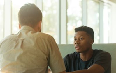 Two men sit across from each other at a table