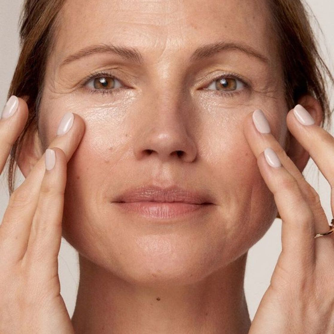 A woman with a tired face, her hands on her face, a sad look—reflecting morning fatigue, puffiness, dull skin, and stress.