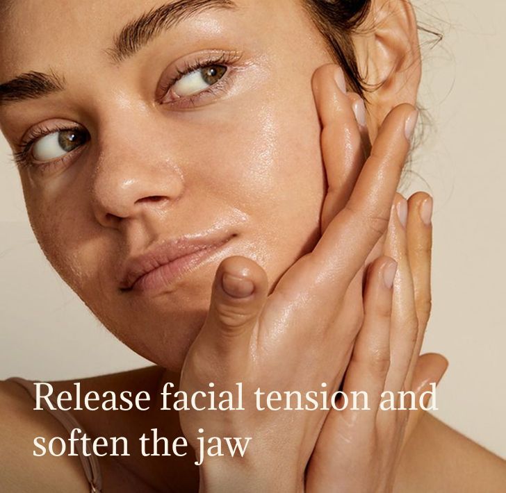 Woman massages her face and jaw, releasing tension and fatigue
