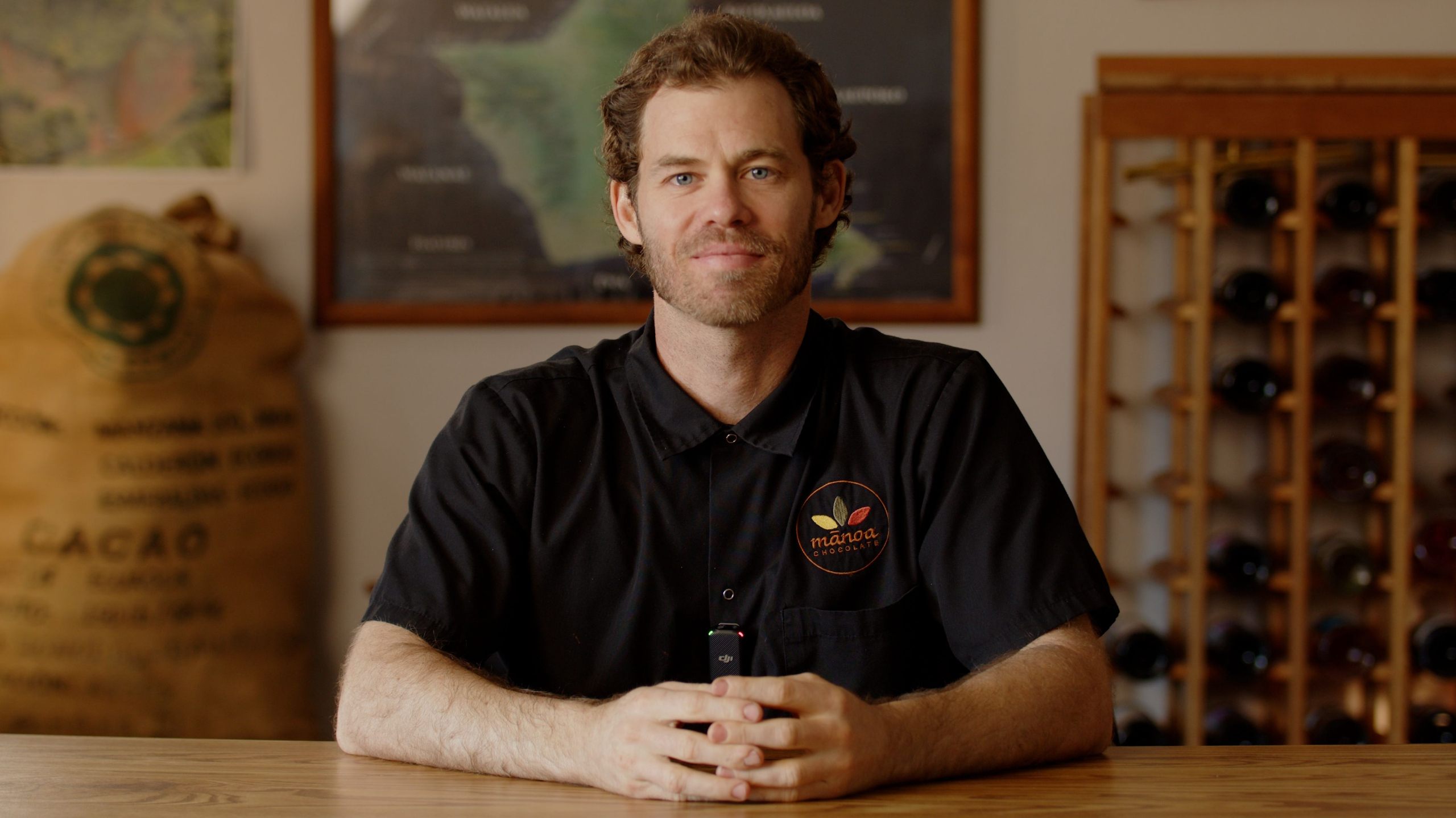 image of man in chef's coat sitting at table smiling