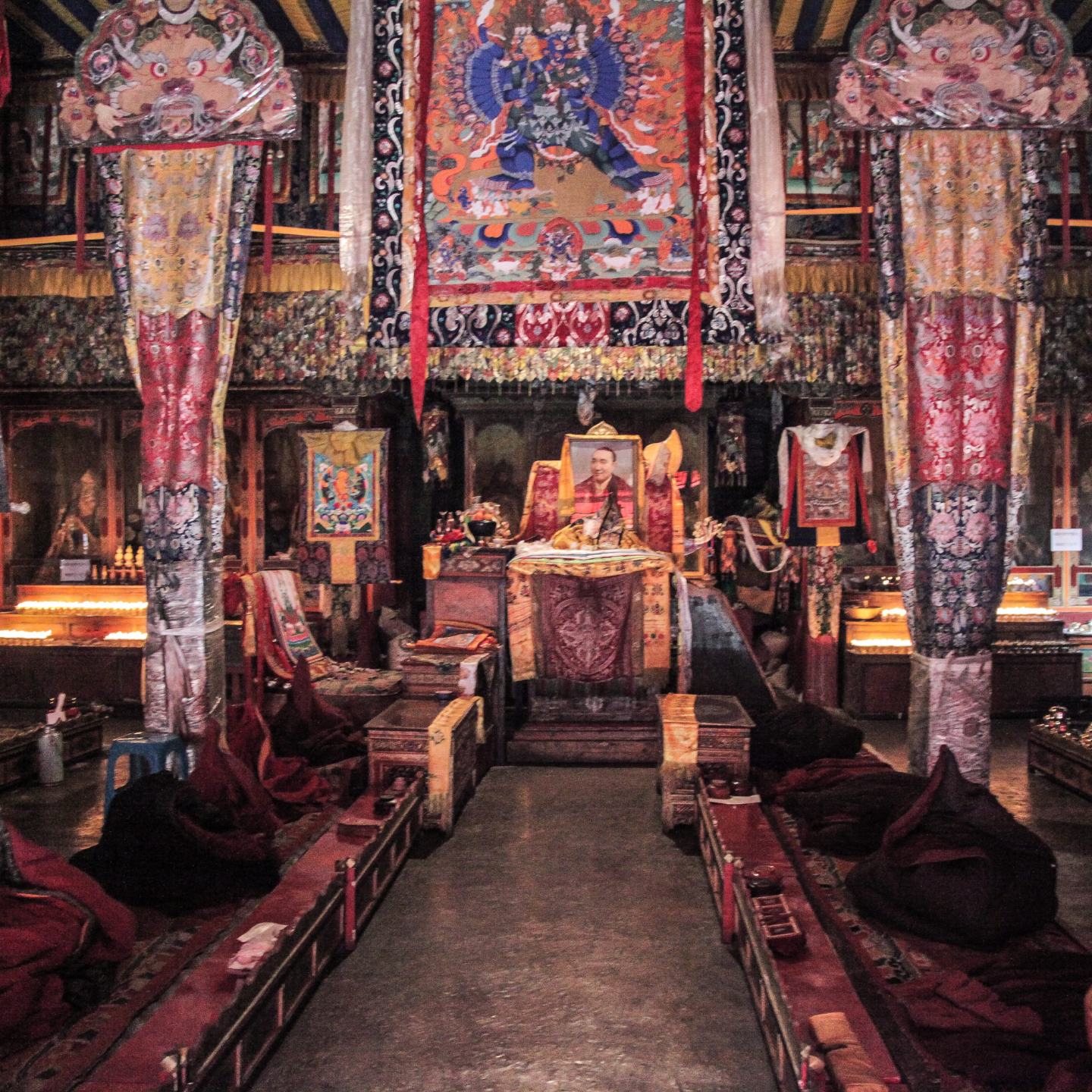 Tibetan monk performing a traditional ritual with drum and scriptures.