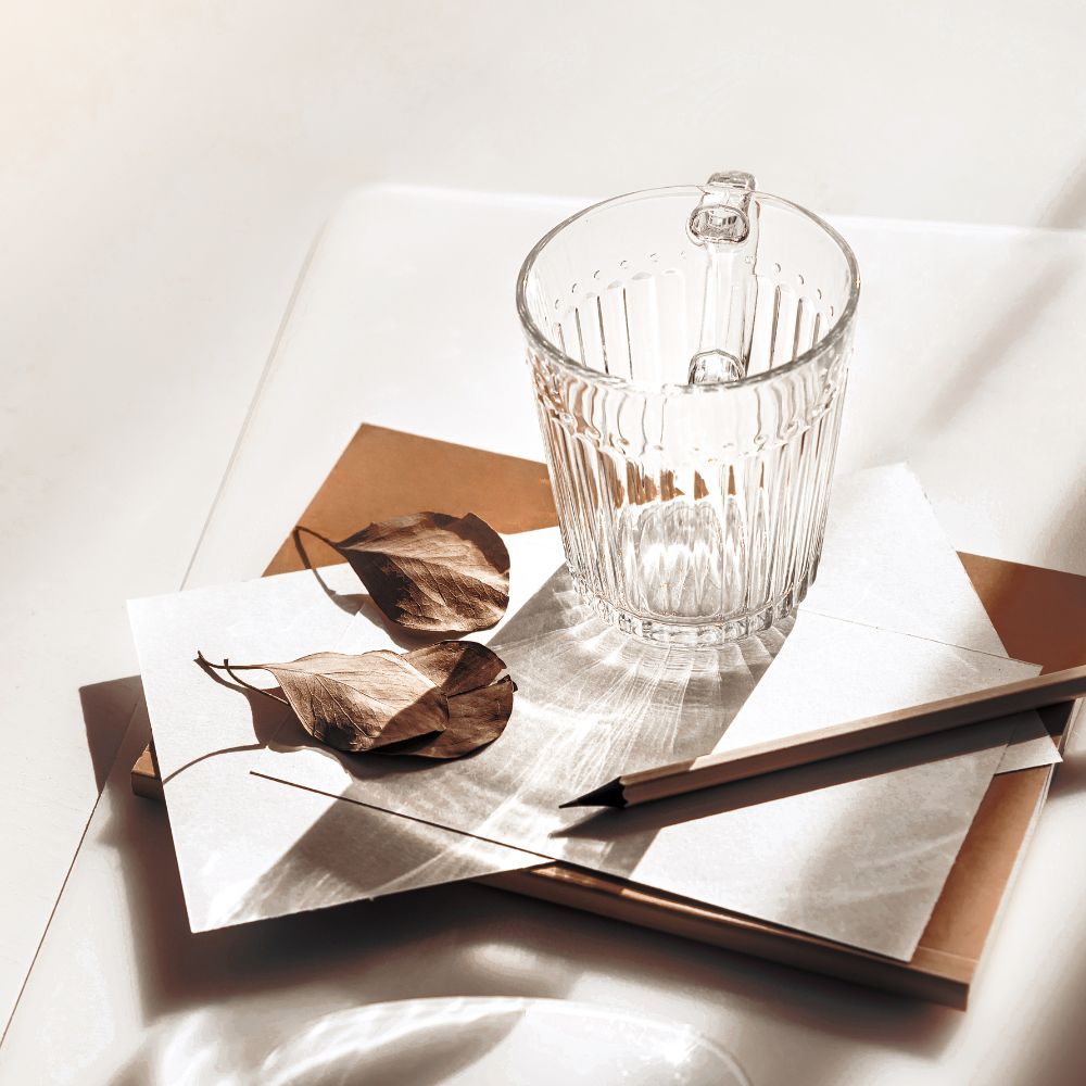 Minimal neutral glass, leaves, pencil