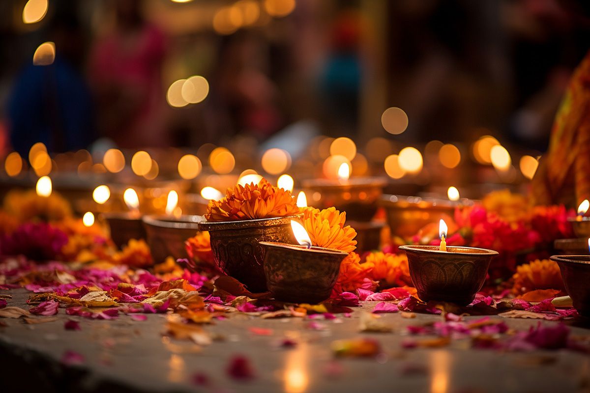 Glowing candles on a table strewn with brightly coloured flower petals.