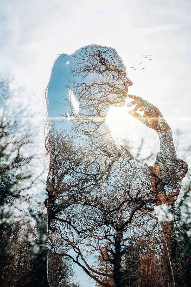 Double exposure of transparent figure with trees showing through behind.  
