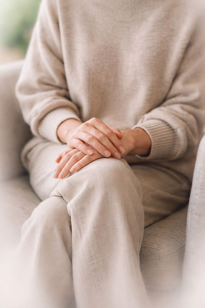 Relaxed woman sitting with her hands on her knee.