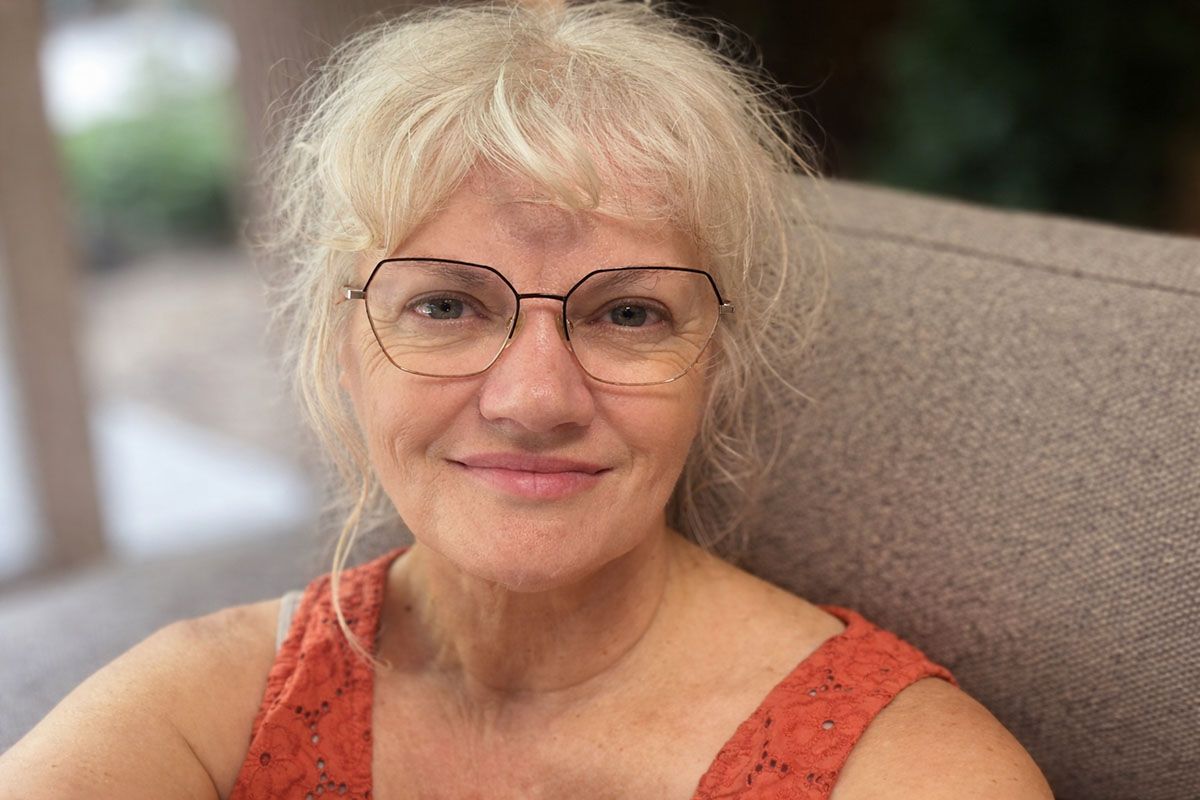 Deborah Christensen smiling while seated on a sofa.
