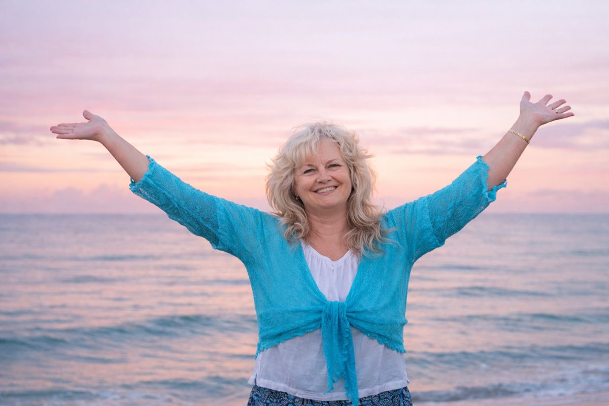 Joyous Deborah Christensen standing by the ocean. 