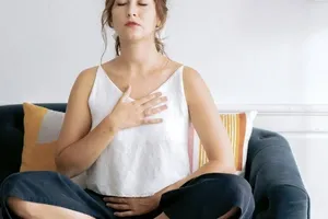 woman smiling while putting her hands on top of her heart