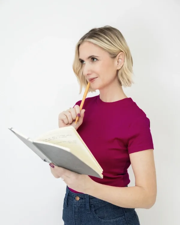 Coach Amanda Doyle smiling while holding a pencil and notebook