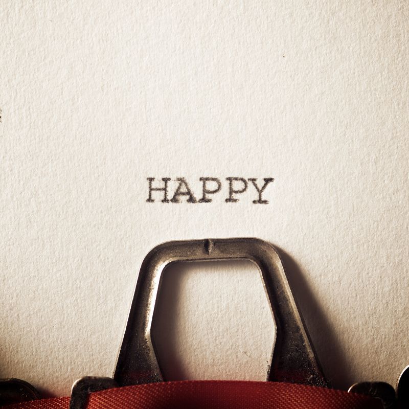 white paper in typewriter with the word happy typed on it