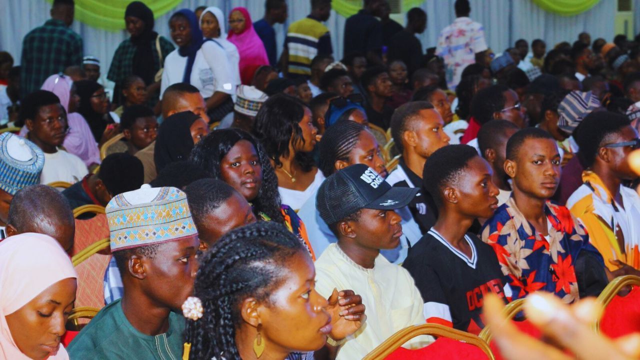 A group of people standing and talking inside a conference room.