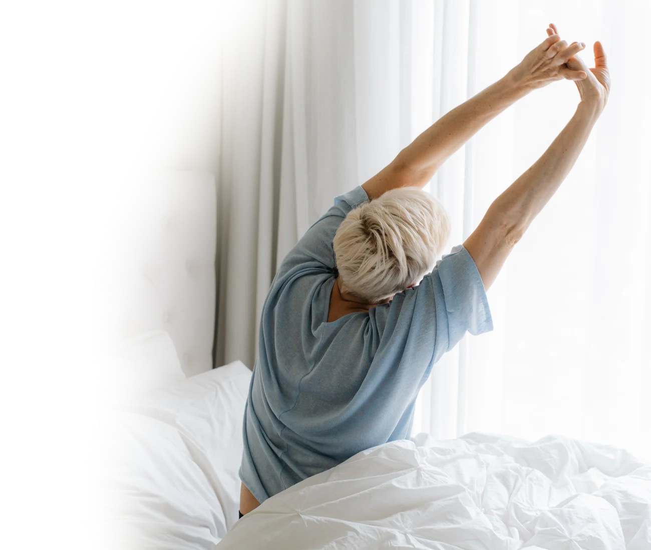 huonosti nukkuva nainen venyttelemässä ikkunan edessä
