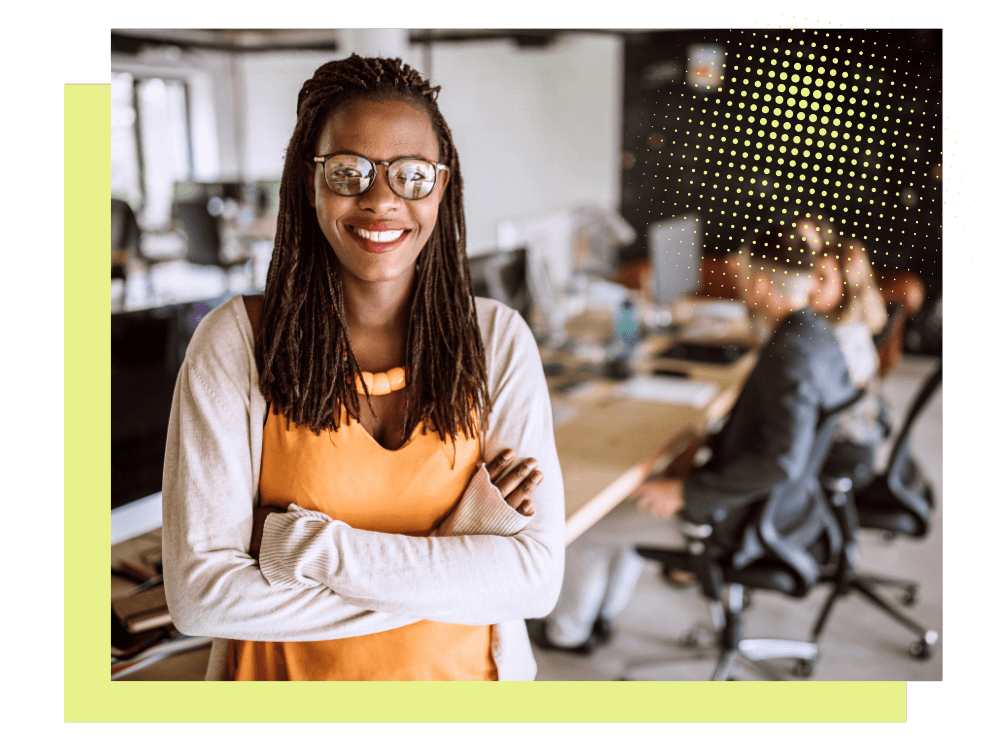 interior shared workspace, smiling woman in foreground with arms crossed