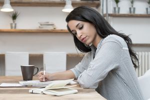 woman writing while looking at her laptop