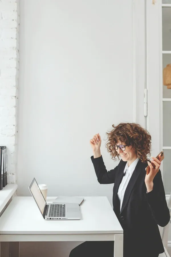 lawyer celebrating while looking at her laptop