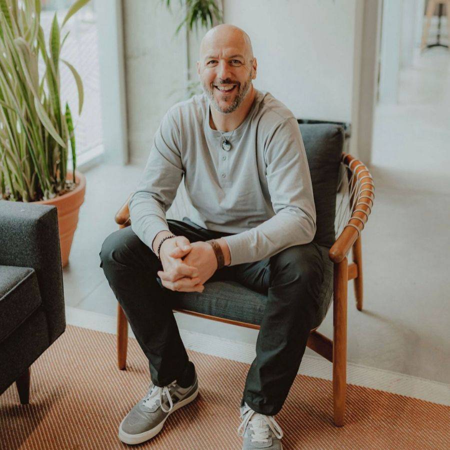 Kevin McNee seated in a wooden chair, smiling