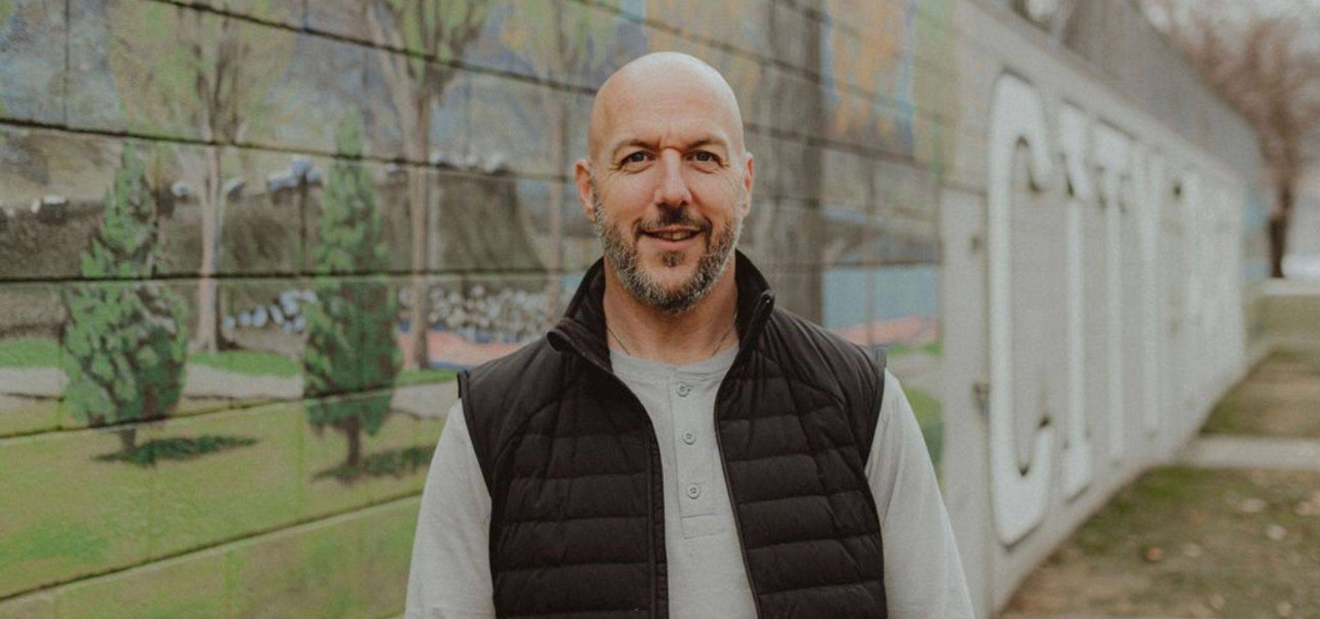 Kevin McNee standing in front of a painted mural