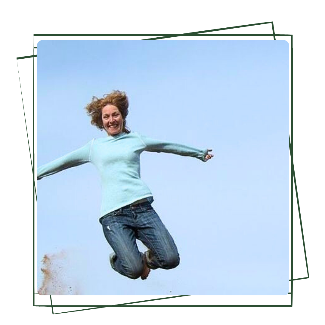 A group of six people sits on the ground outdoors under a blue sky, with mountains in the distance, embracing nature connection. Some wear hats and sunglasses.