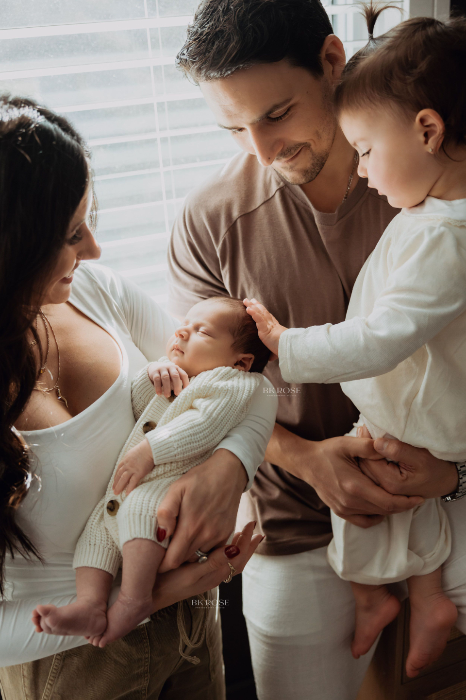 family of 4 looking at newborn baby