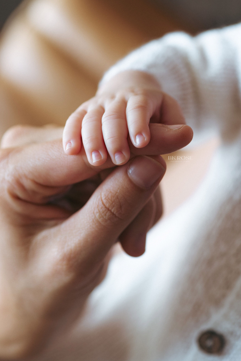 newborn baby holding the hand of a woman