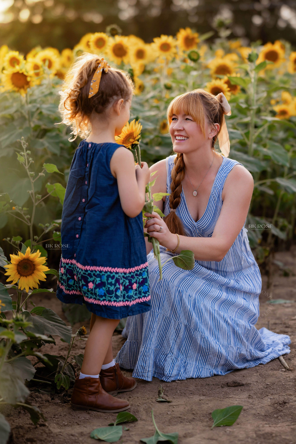 mother sharing sunflowers with her daughter in a sunflower field