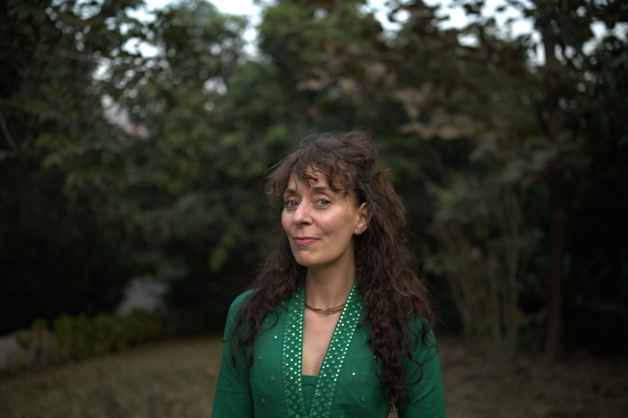 Portrait of Bobbie Marchand, yoga asana teacher, standing outdoors at Govardhan Eco Village in India.