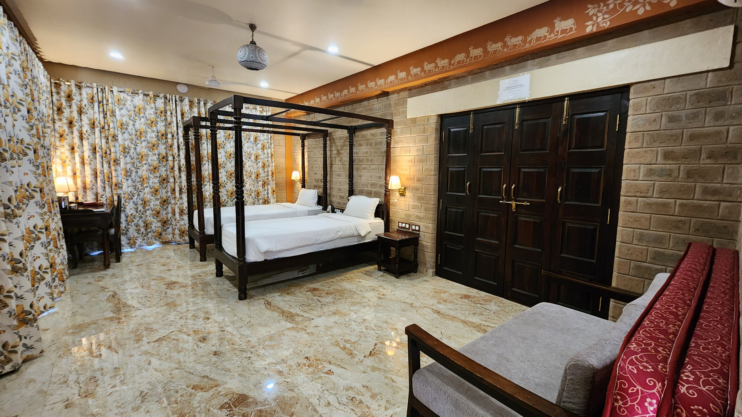 Spacious twin room accommodations at Govardhan Eco Village in India, featuring earthen brick walls, handcrafted wood beds, and modern comforts for yoga teacher training participants.