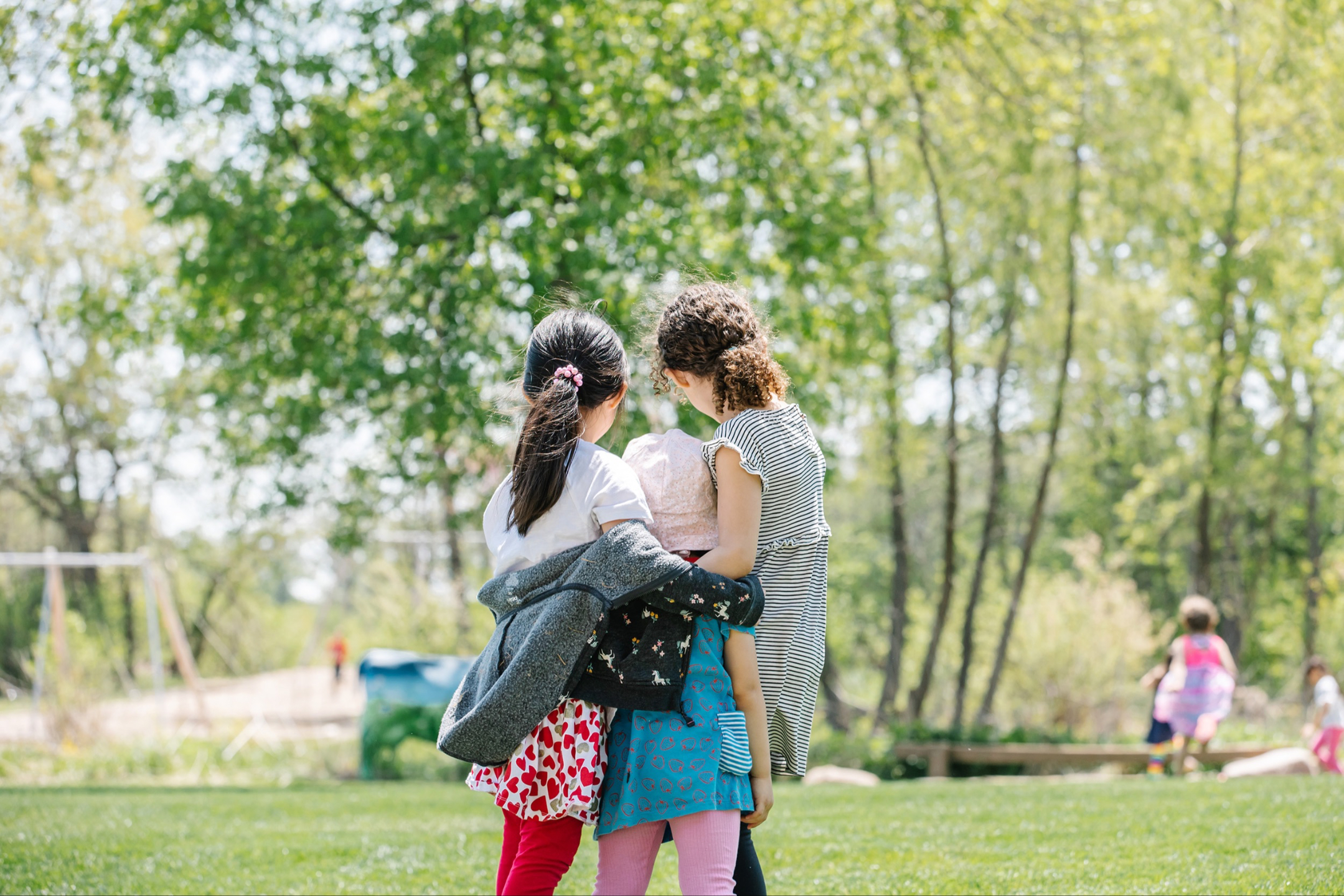 children looking away at a park with arms around each other