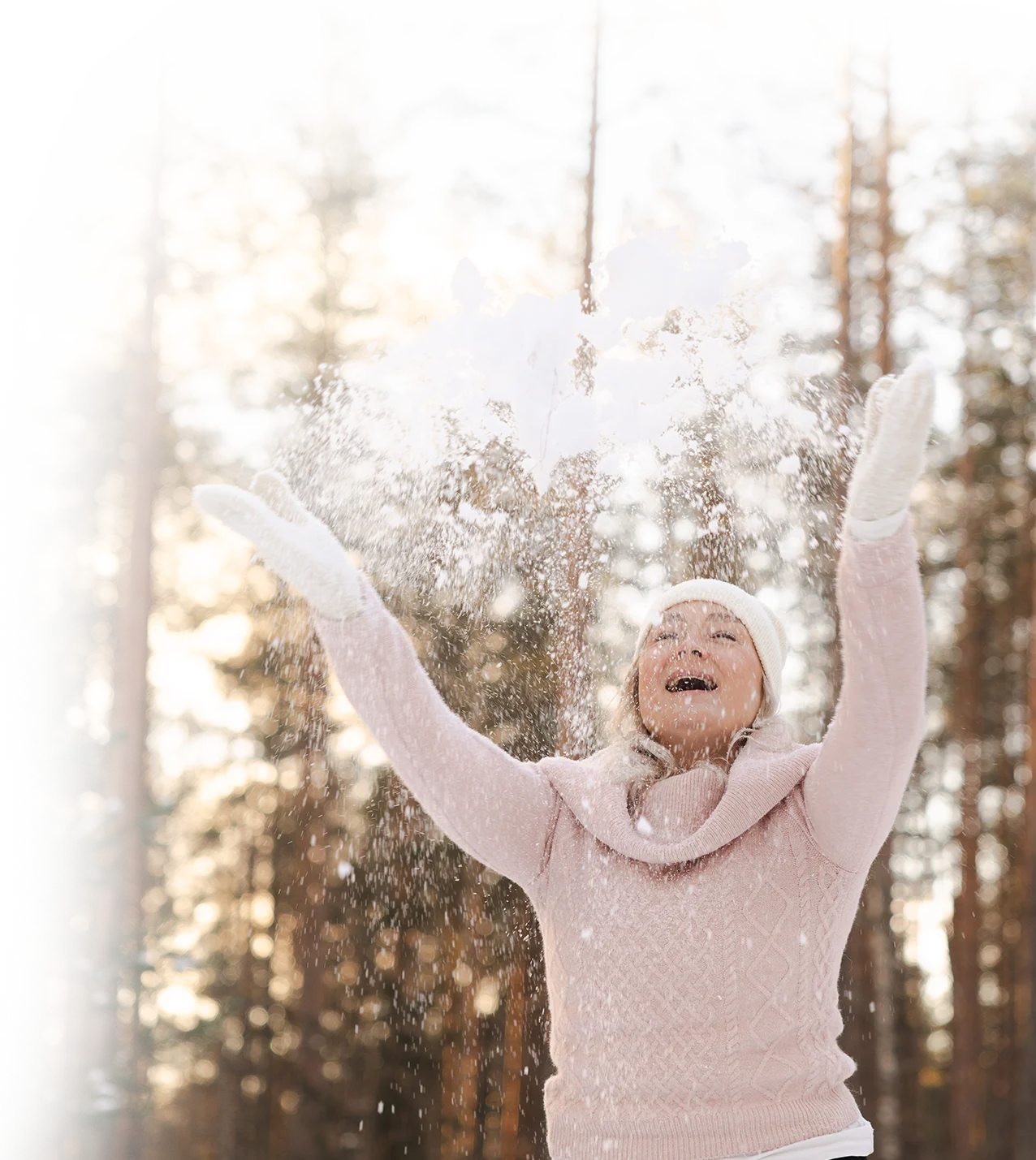 hyvinvointivalmentaja heittää iloisesti lunta ilmaan talvisessa maisemassa