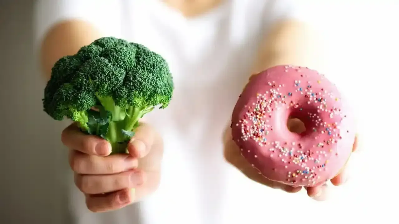 Persona holding broccoli and a donut