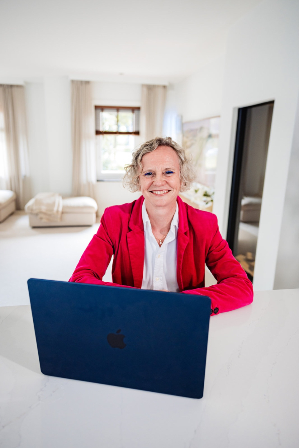 Jet wearing a bright magenta jacket sitting behind her laptop