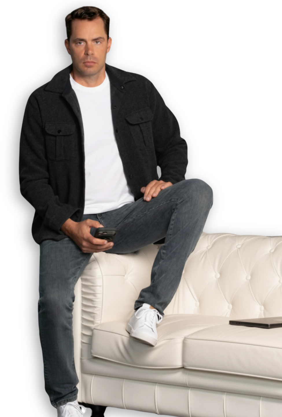 Eric Canori, high-performance consultant for entrepreneurs and leaders sitting on a sofa arm with phone in his hand