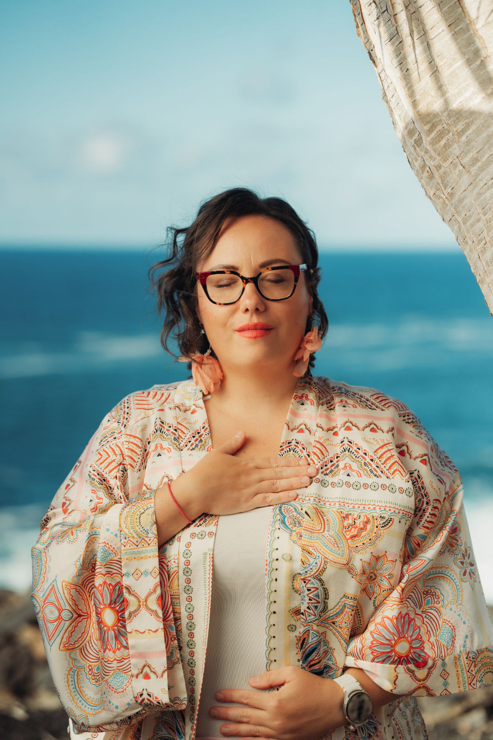 Vas Tímea a Nagylevegő podcastból mosolyogva lélegzik mélyen trópusi kertben, narancssárga virágok között