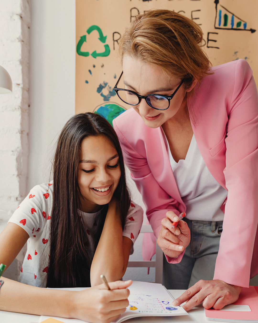 An instructor leaning over to guide a student as they work through an exercise together, showing how human feedback, sequencing, and support turn information into a meaningful learning experience.