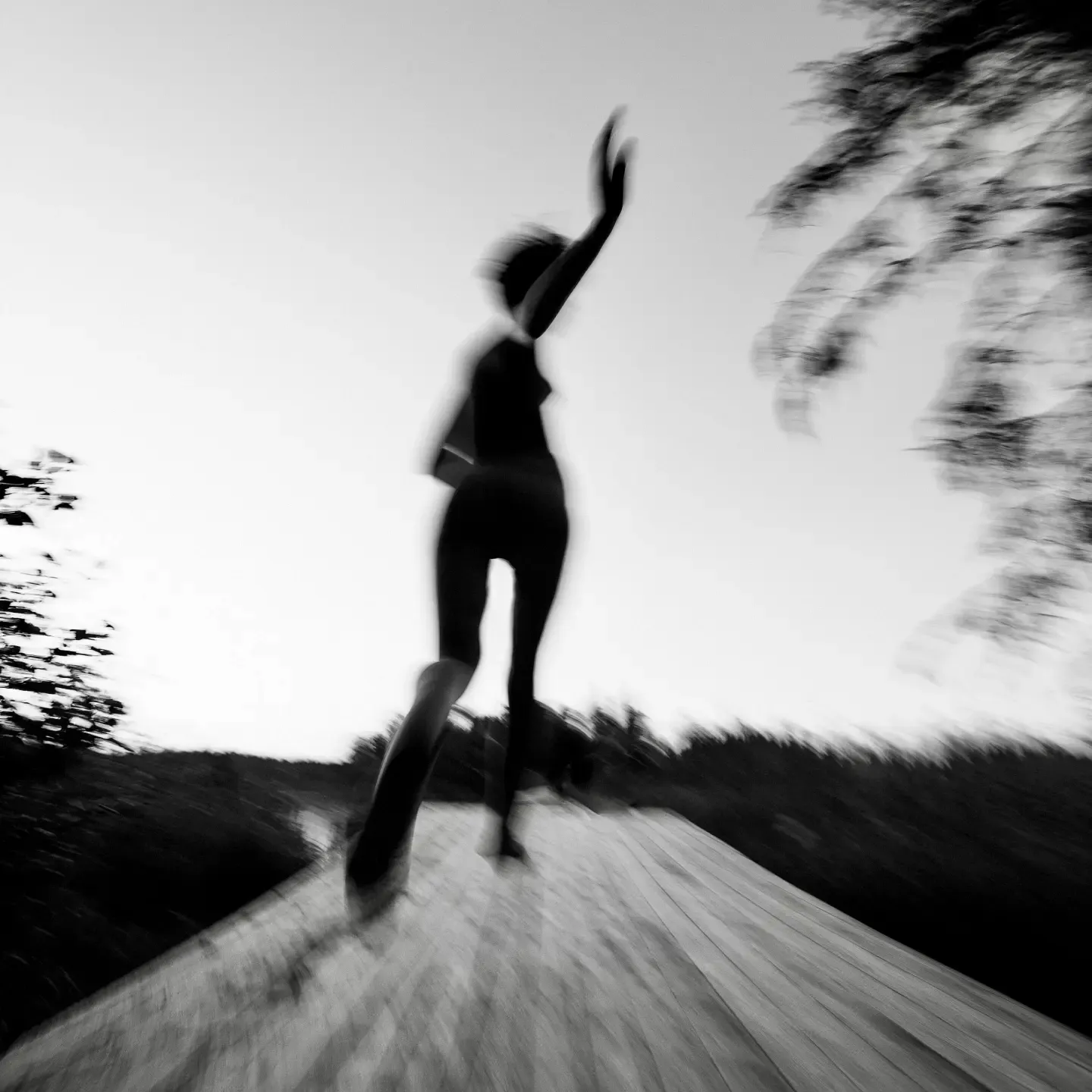 Silhouette of a person standing on a path with arms raised in a gesture of freedom and ease.
