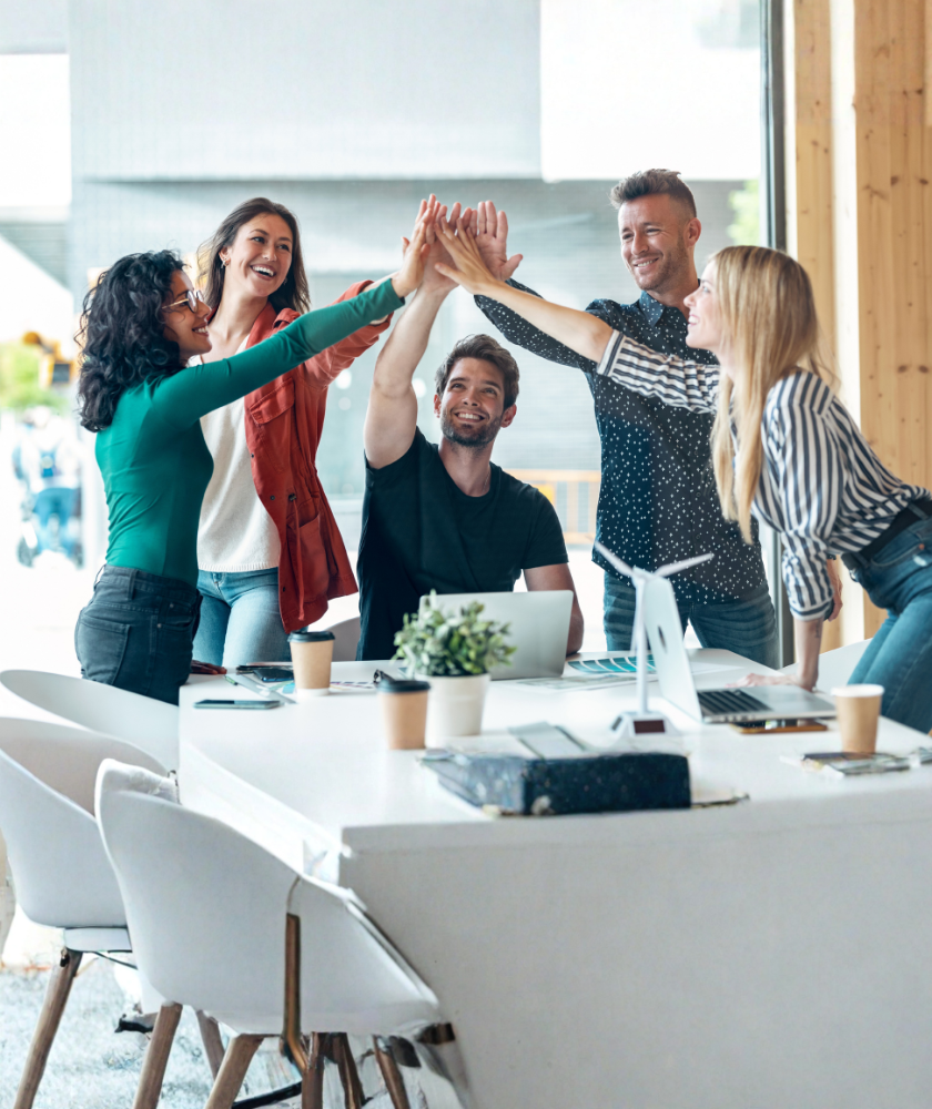 Professional coaches and clients celebrating progress during a team coaching and leadership development session.