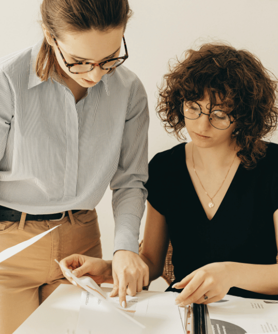 Two people reviewing printed dashboard layouts together at a desk, discussing structure, spacing, and design decisions.