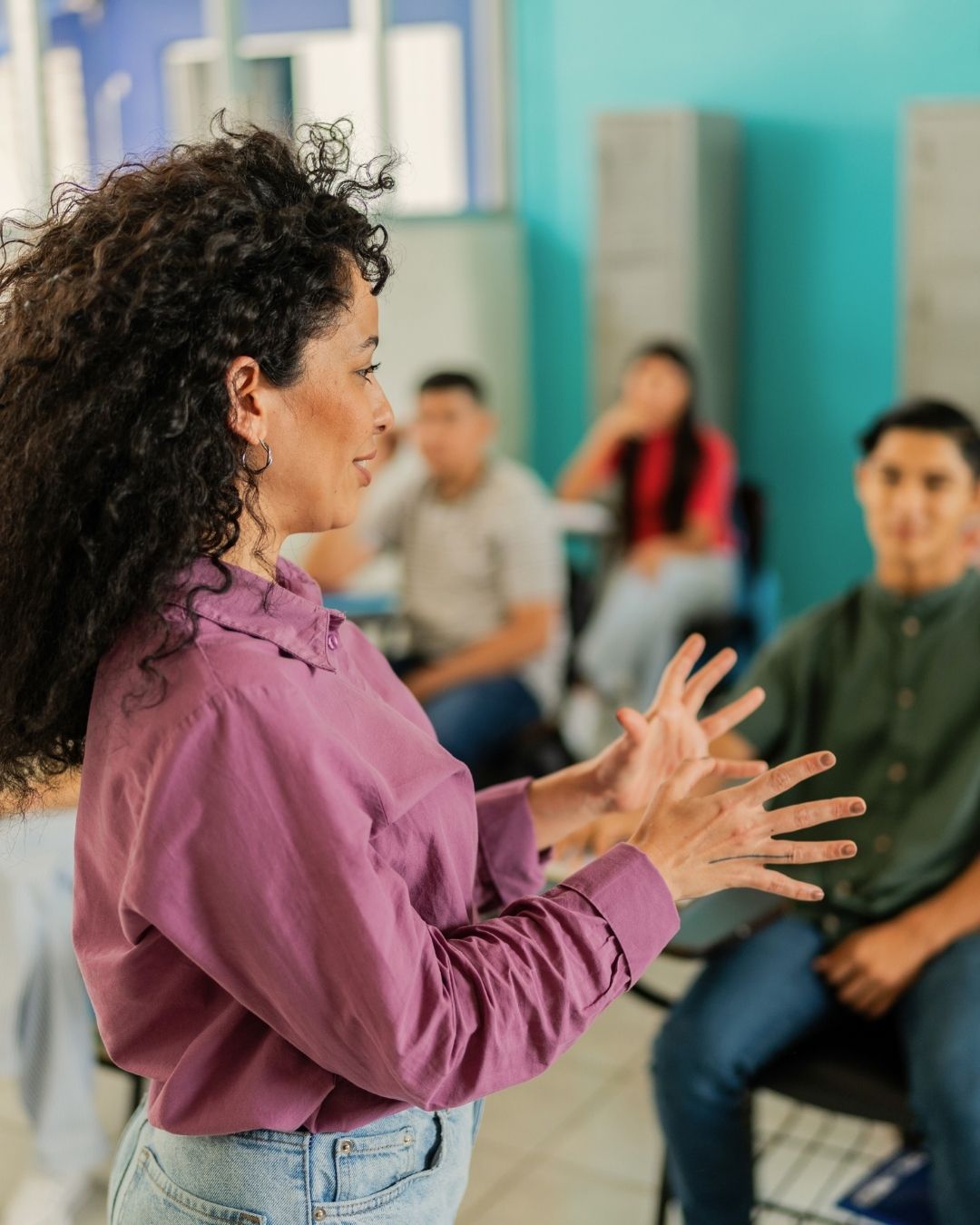 A facilitator speaking to a small group seated in a circle, illustrating how human presence, guidance, and real-time interaction continue to support learning outcomes beyond content alone.