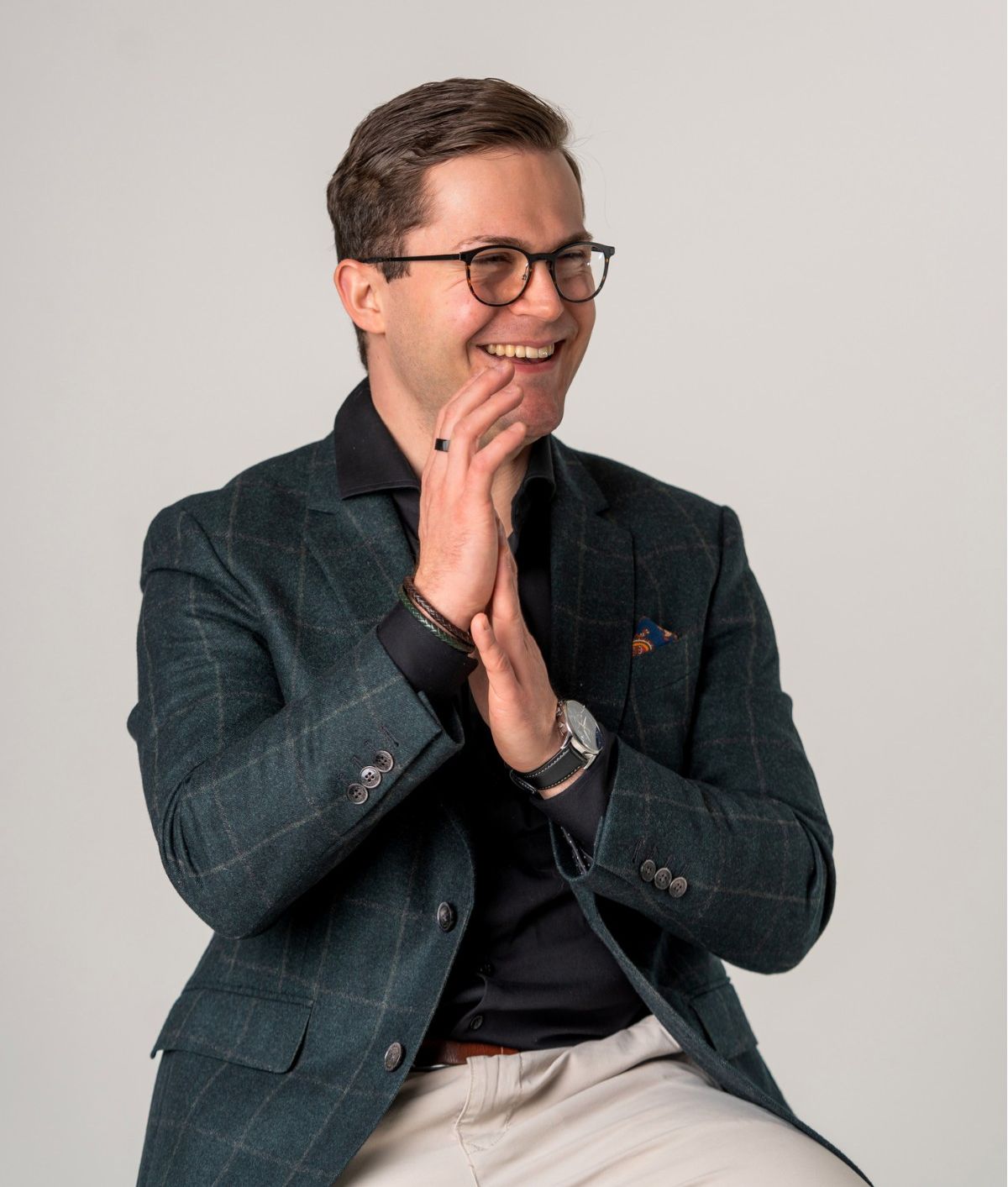 Erich Lirzer sitzt auf einem Hocker und lacht