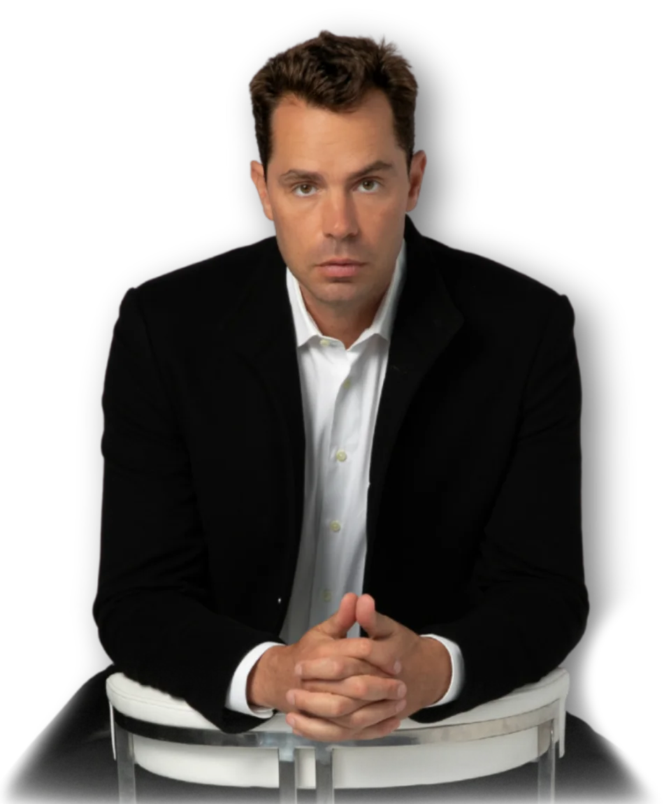 Eric Canori, high-performance consultant for entrepreneurs in a black suit sitting on a chair