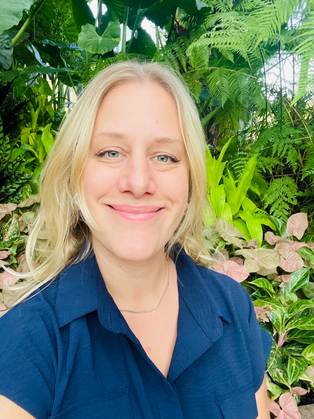 Elena Ramsey, registered nurse and health and wellness coach, standing by plants