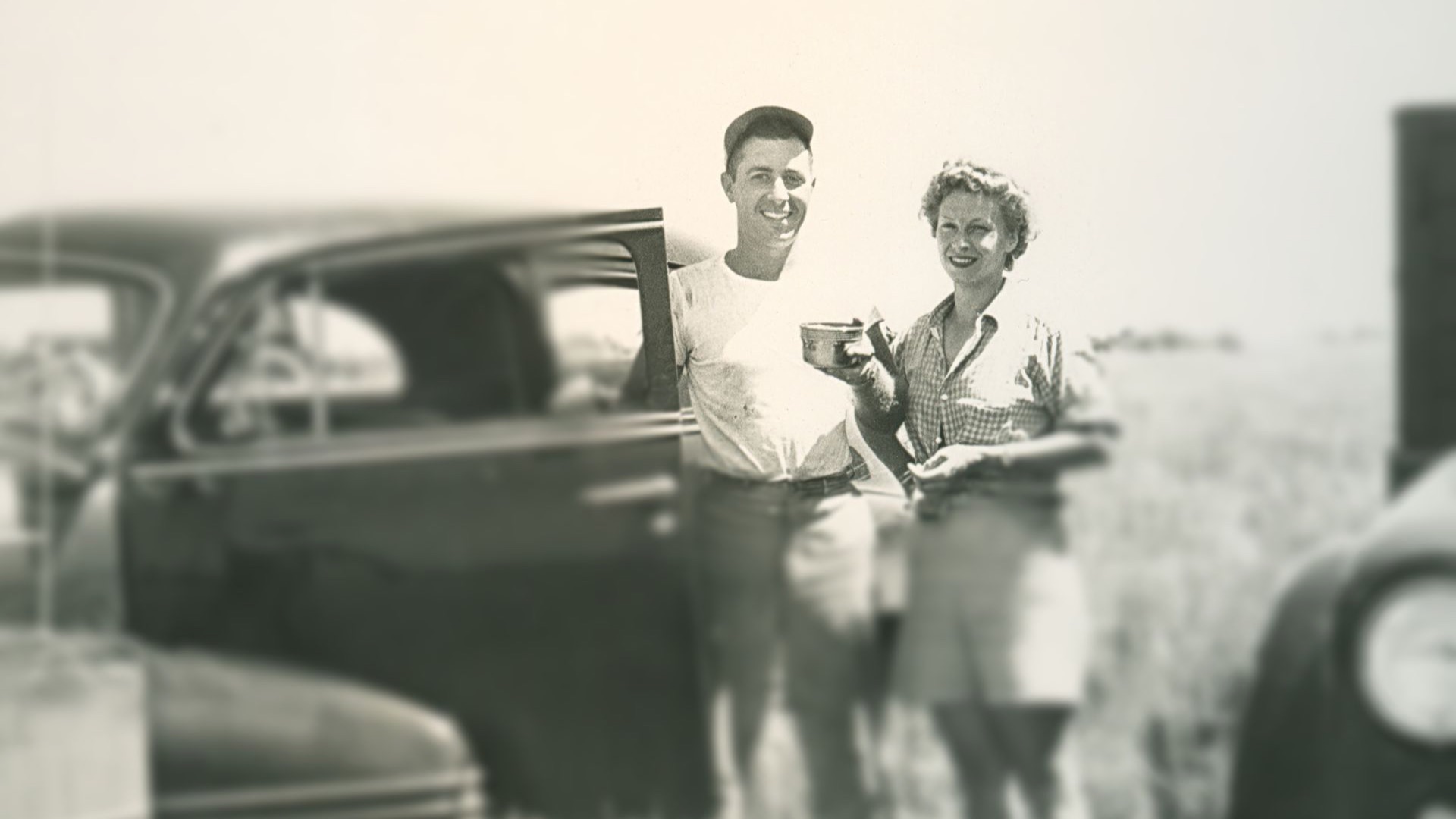 Man and woman standing by car in a field