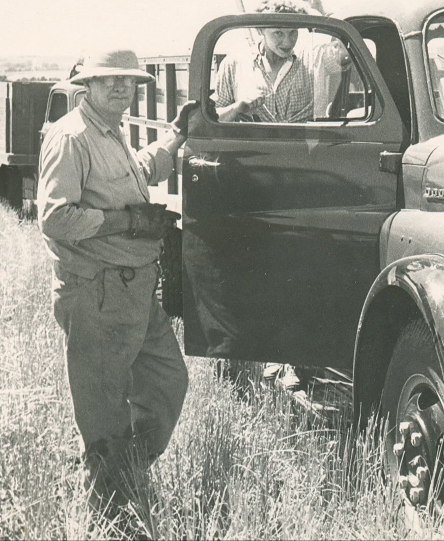black and white photo of man holding truck door in a field