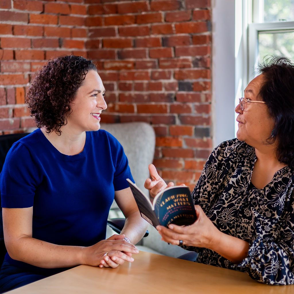 Erica with a client, who holds a copy of Erica's book "Clarifying What Matters"