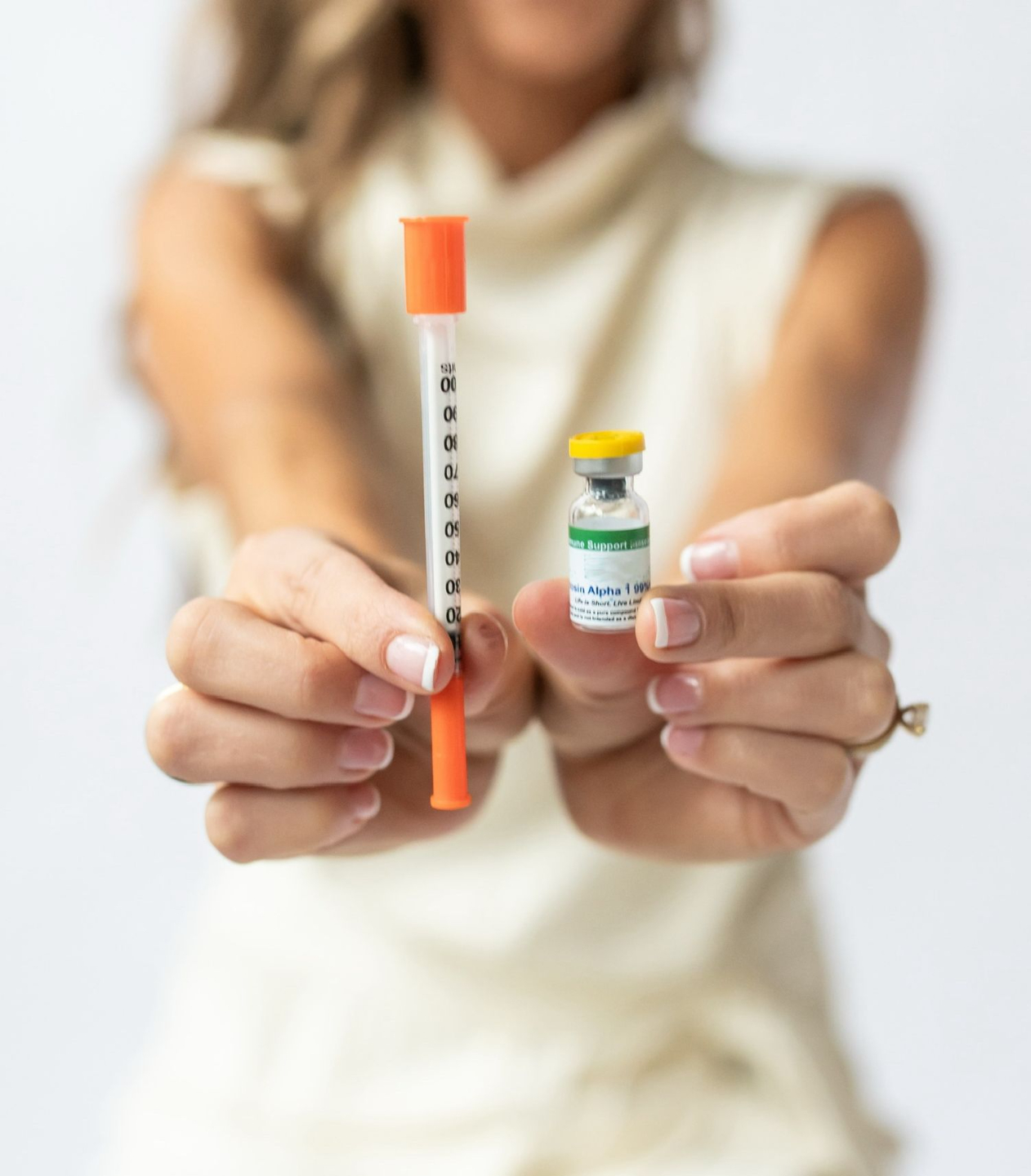 Woman holding a syringe on one hand and a vial on another