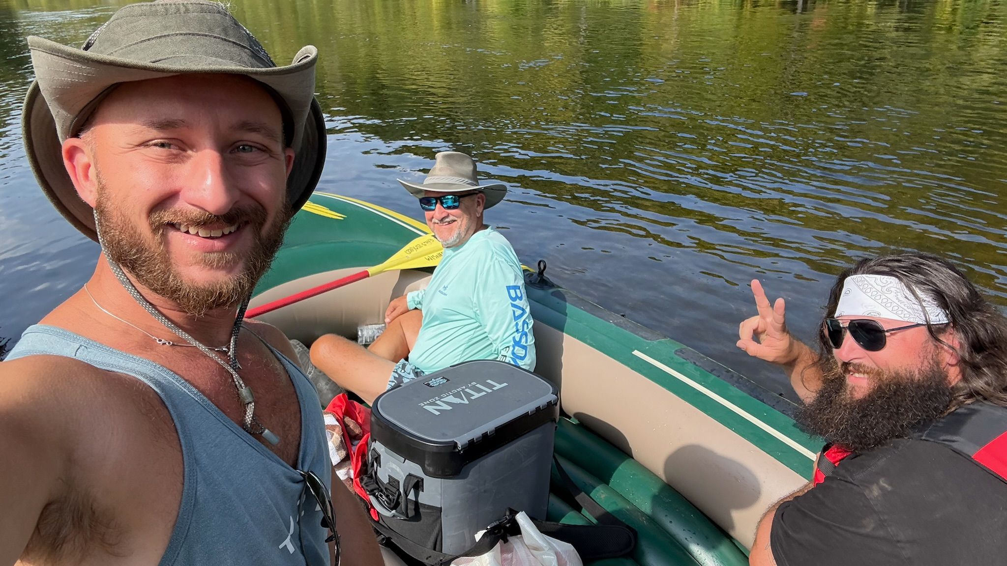 Three men laughing and rafting on the Muskegon River during a past Metro-Detroit Men's Therapy retreat in northern Michigan