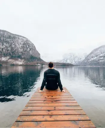 laptop next to yellow coffee mug and tan basket containing a green plant