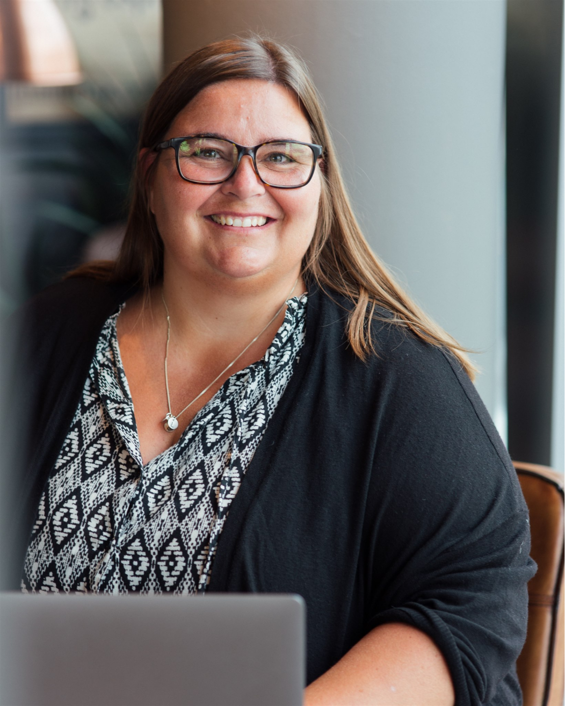 Astrid Valen-Utvik sitter ved pc, smiler og ser i kamera