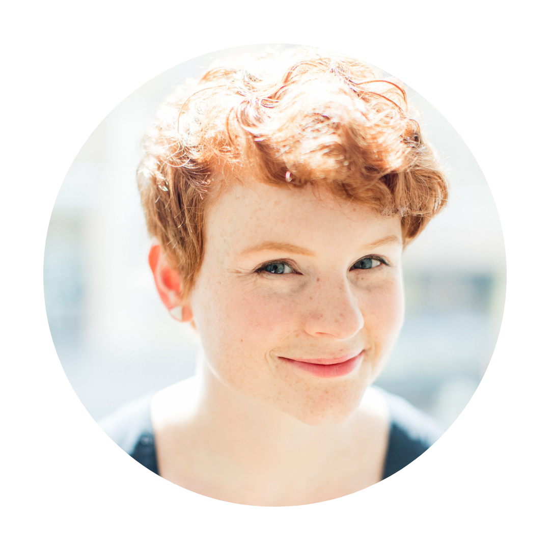 A headshot of Nic Gagliardi, and individual with short curly red hair, looking directly at the camera.
