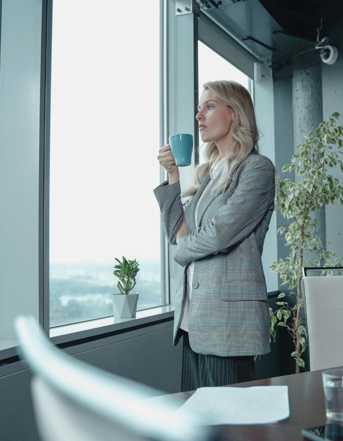 Business woman at window with mug thinking